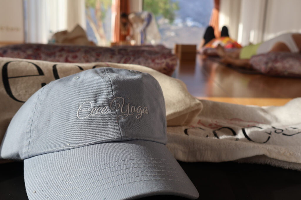 Close-up of Cece Yoga branded cap with yoga mats and bolsters in the background in Amorgos, Greece