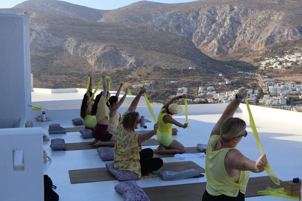 Yoga class stretching with resistance bands on a rooftop overlooking Amorgos village in Greece