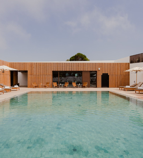 Modern wooden retreat villa with a serene outdoor pool and sun loungers in Portugal.