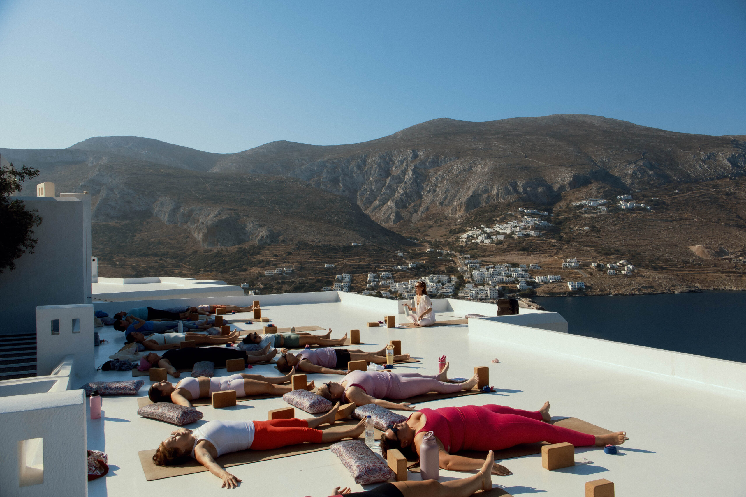 Women practicing yoga outdoors with mountain and sea views in Amorgos, Greece